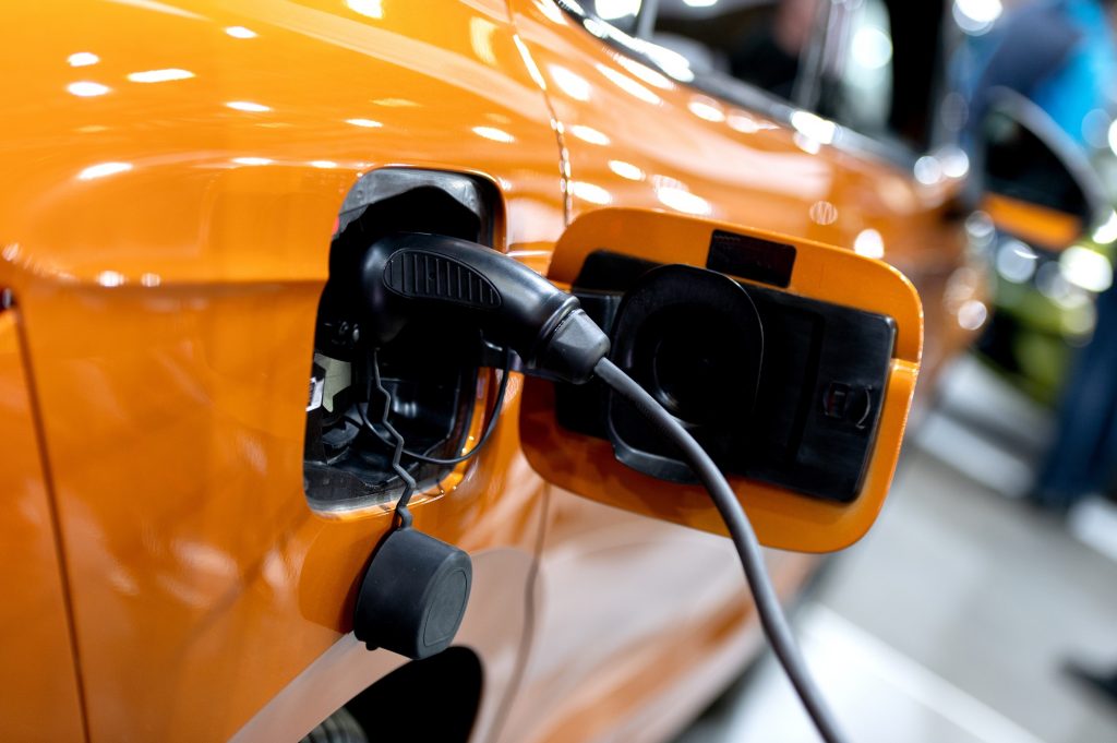 Closeup of power supply plugged into an modern electric car. Electric or EV car charging station.
